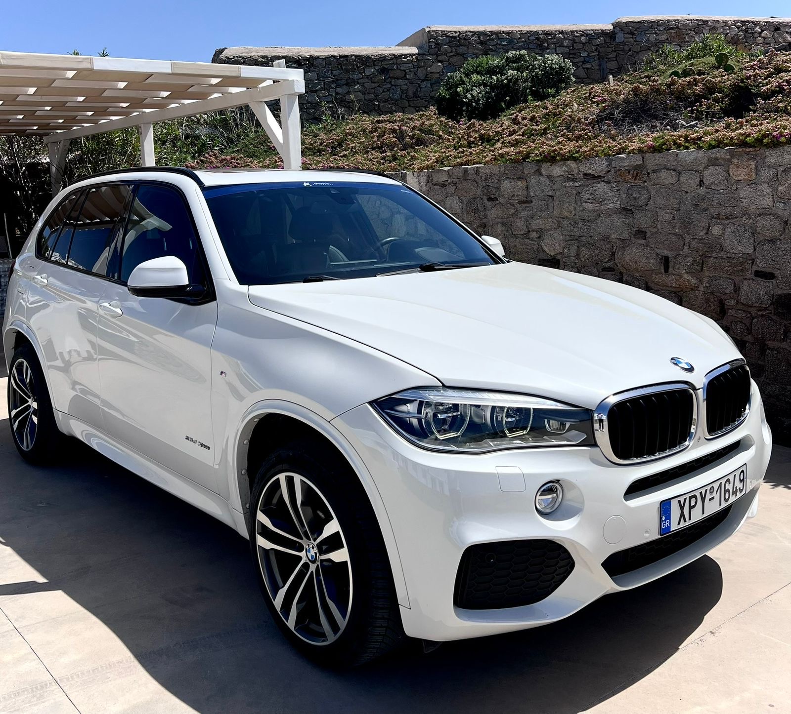 White BMW X5 parked at a stone villa on Mykonos