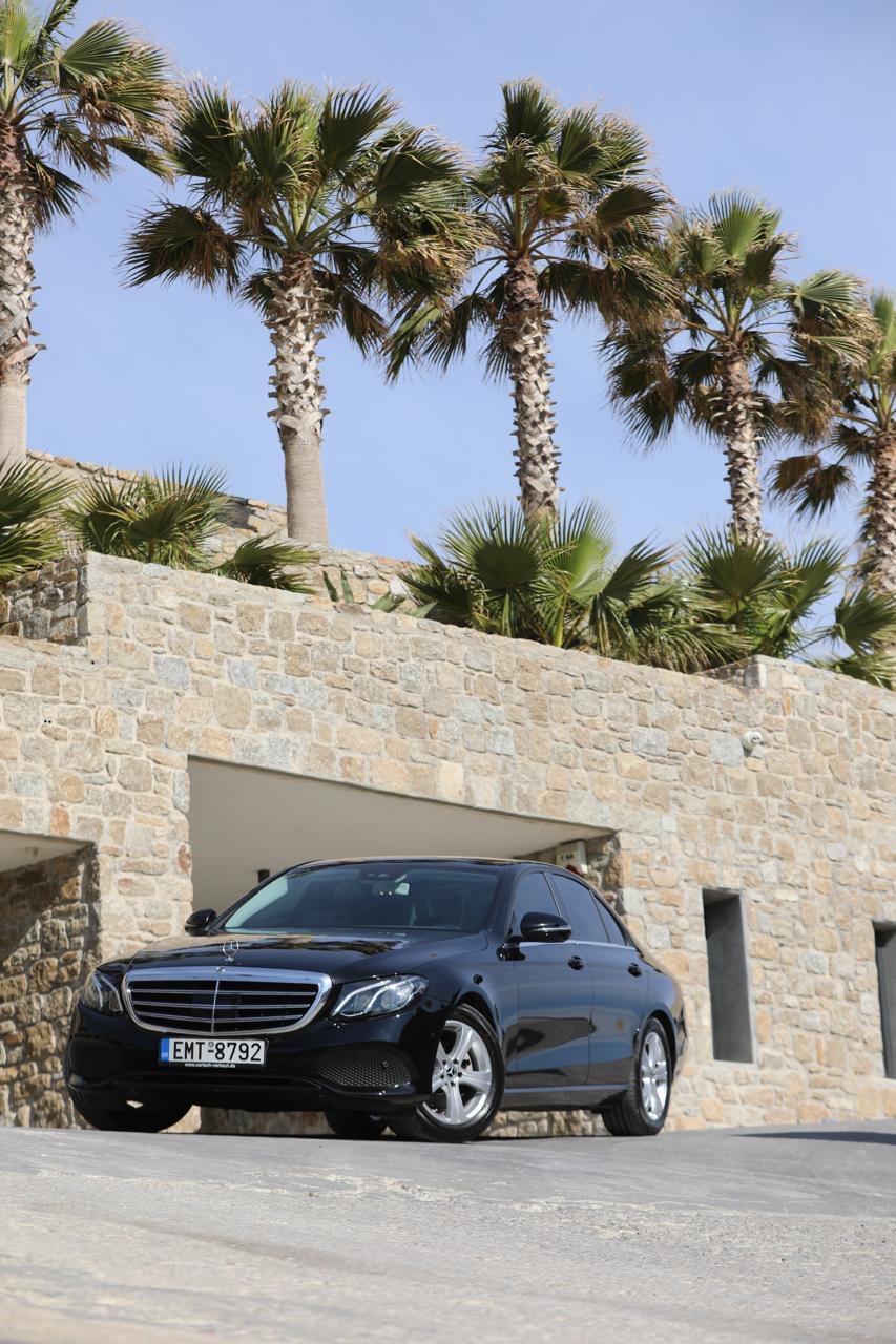 Black Mercedes E-Class below palm trees on Mykonos