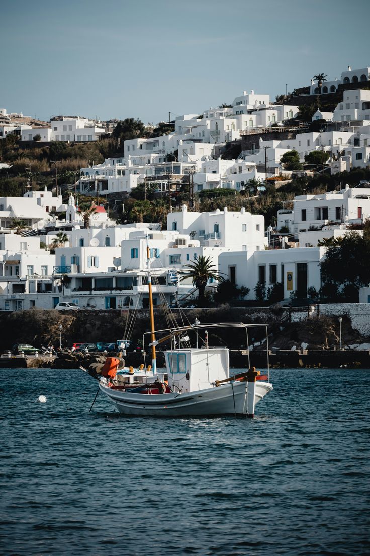 Fishing boat in the old port of Mykonos beneath the white houses of Chora
